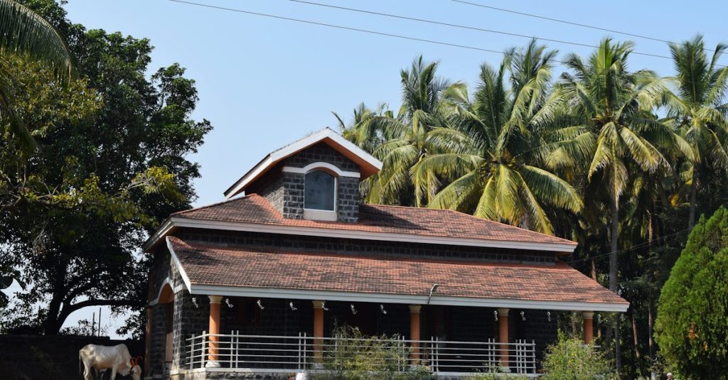 A beautiful rural house with a red roof and palm trees, showcasing serene countryside life.